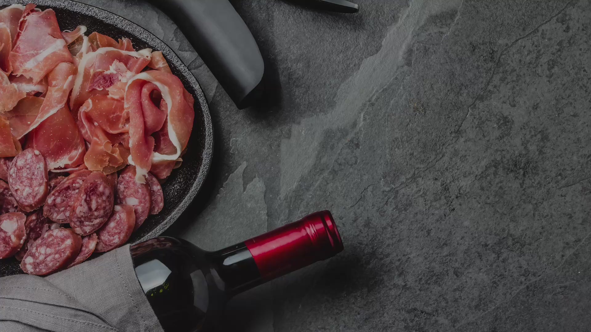 Verschiedene Delikatessen wie Schinken (Jamón), Käse (Queso), Wein (Vino) und Olivenöl (Aceite de Oliva).